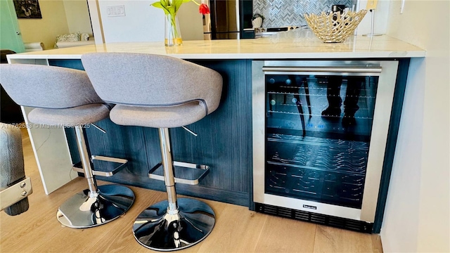 bar with beverage cooler, tasteful backsplash, and wood finished floors