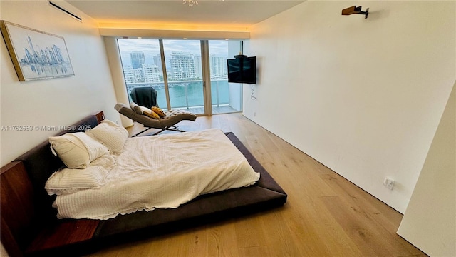 bedroom featuring a wall of windows, light wood-type flooring, and access to outside