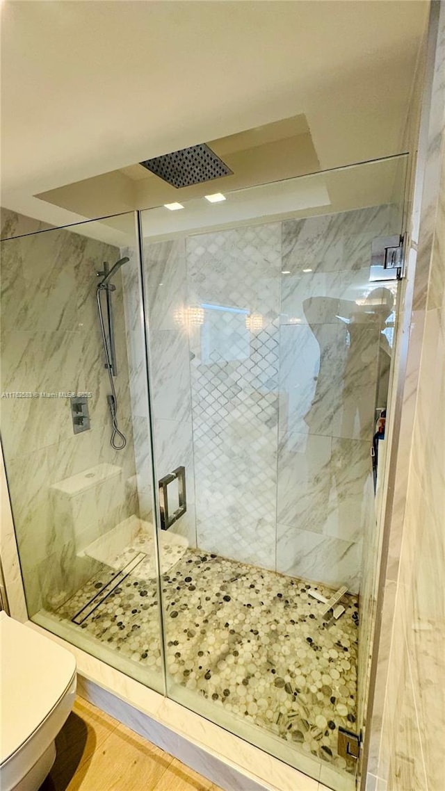 full bath with toilet, wood finished floors, and a marble finish shower