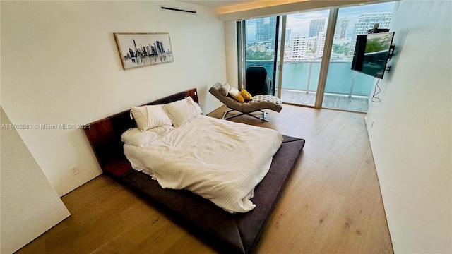 bedroom featuring wood finished floors, floor to ceiling windows, and access to outside