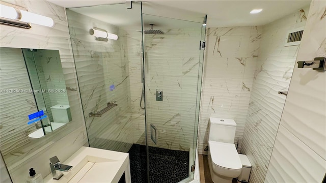 full bathroom featuring a marble finish shower, tile walls, toilet, and visible vents