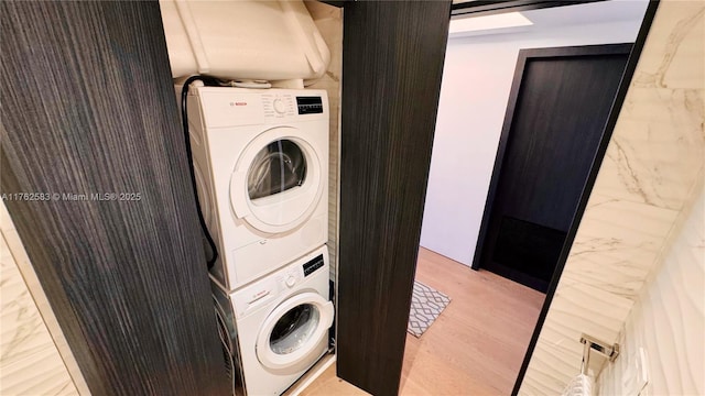 washroom featuring stacked washer and dryer, light wood-style flooring, and laundry area