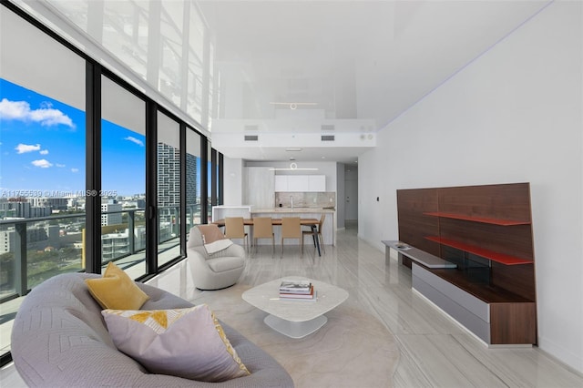 living area with expansive windows, a city view, and a towering ceiling