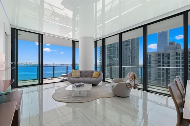 living area with tile patterned flooring, floor to ceiling windows, a view of city, and a water view