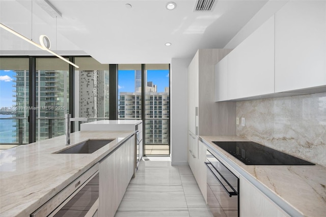 kitchen featuring black appliances, modern cabinets, tasteful backsplash, and visible vents