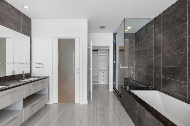 full bath featuring visible vents, a walk in closet, a stall shower, a bath, and vanity