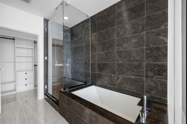 full bathroom featuring marble finish floor, a shower stall, a bath, and a spacious closet