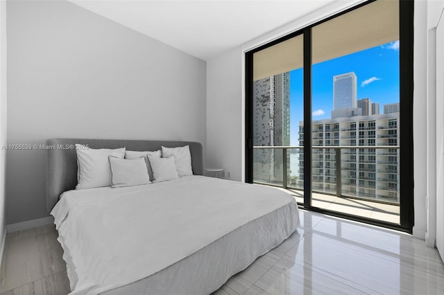 bedroom with a view of city, floor to ceiling windows, access to exterior, and marble finish floor