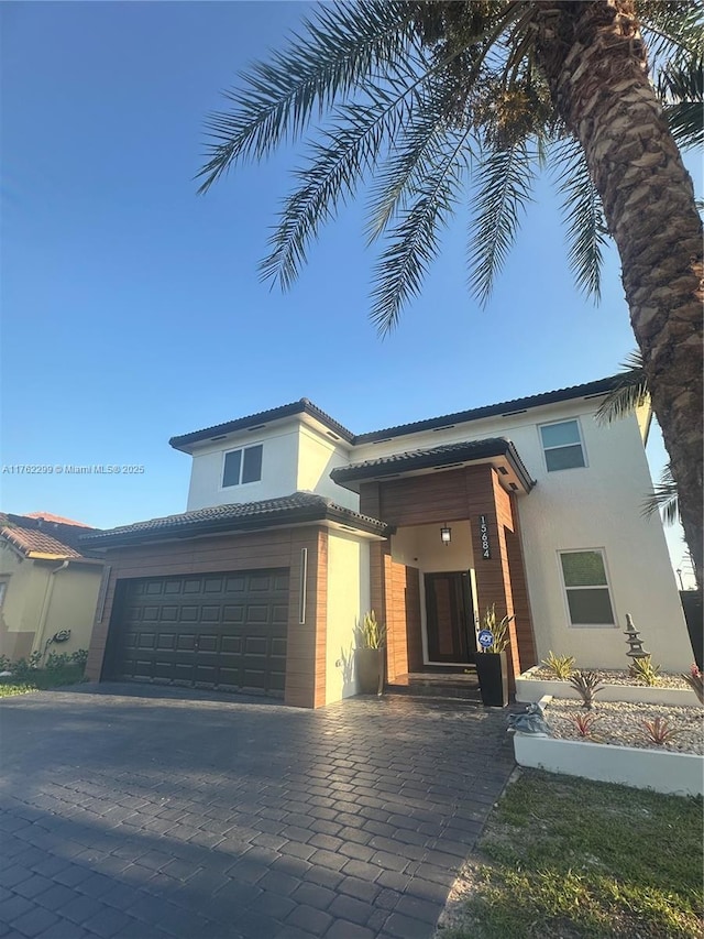 view of front of house with stucco siding, decorative driveway, an attached garage, and a tiled roof