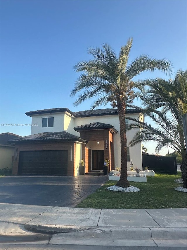 view of front of house featuring stucco siding, an attached garage, driveway, and a tiled roof