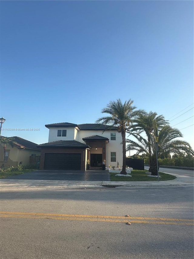 mediterranean / spanish home featuring a tiled roof, driveway, and stucco siding