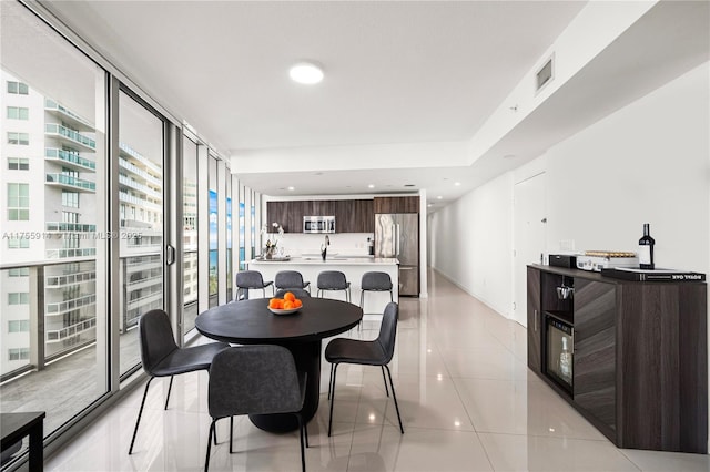 dining room with visible vents, baseboards, a wall of windows, light tile patterned floors, and recessed lighting