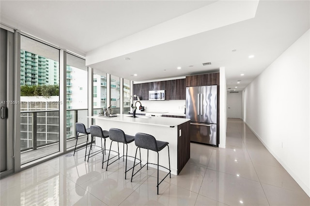 kitchen featuring a kitchen bar, modern cabinets, appliances with stainless steel finishes, light countertops, and light tile patterned floors