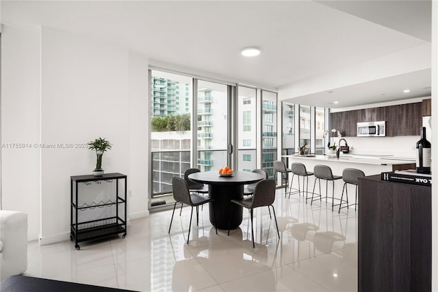 dining area featuring light tile patterned flooring, recessed lighting, a wall of windows, and baseboards