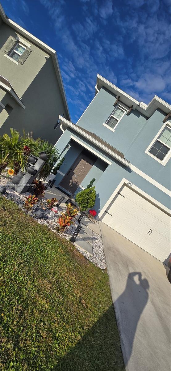 view of side of property featuring concrete driveway, an attached garage, and stucco siding