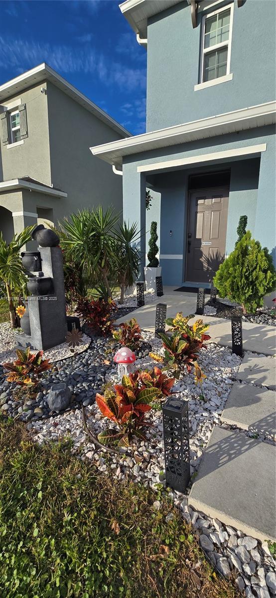 entrance to property with covered porch and stucco siding