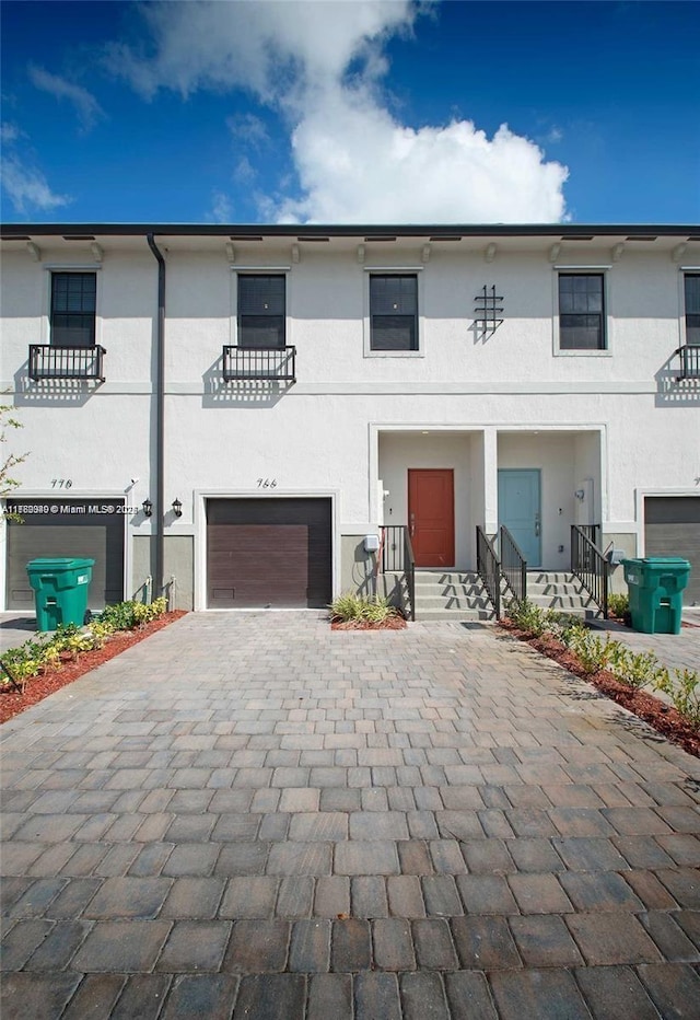 view of property featuring decorative driveway, a garage, and stucco siding