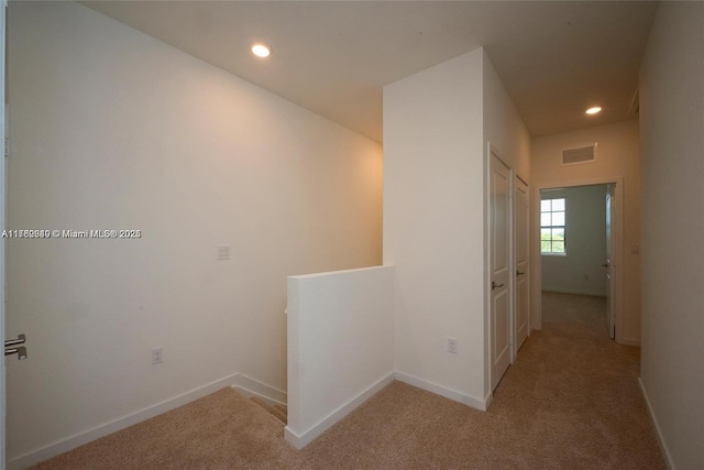 hall with an upstairs landing, visible vents, recessed lighting, and light colored carpet