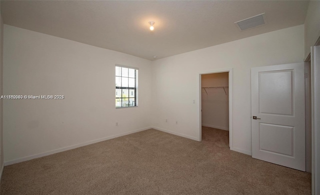 unfurnished bedroom with visible vents, a closet, carpet floors, baseboards, and a spacious closet