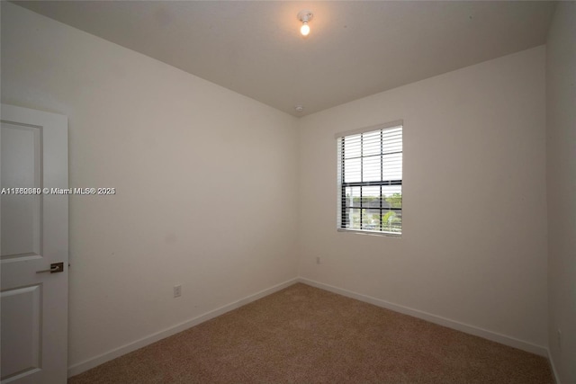 carpeted spare room featuring baseboards