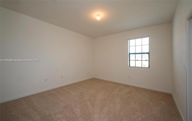 spare room featuring baseboards and light carpet