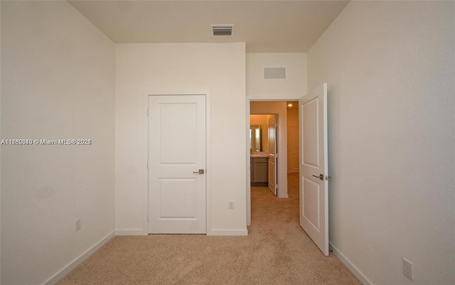 unfurnished bedroom featuring baseboards, visible vents, and light carpet