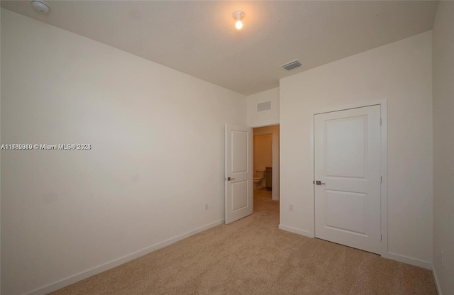 unfurnished bedroom featuring light colored carpet, visible vents, and baseboards