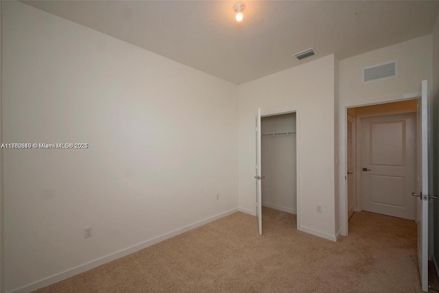 unfurnished bedroom featuring a closet, visible vents, light colored carpet, and baseboards