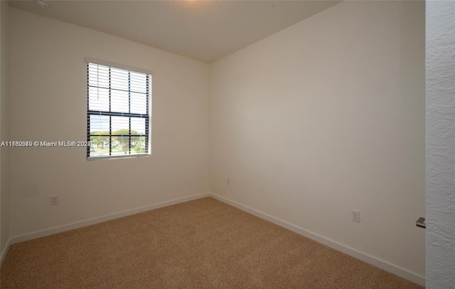 carpeted spare room featuring baseboards