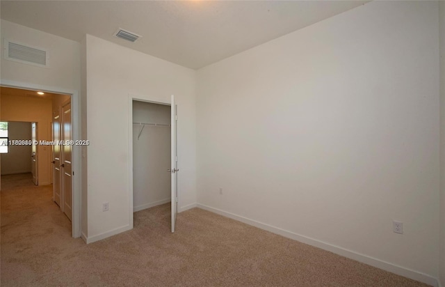 unfurnished bedroom featuring visible vents, baseboards, light colored carpet, and a closet