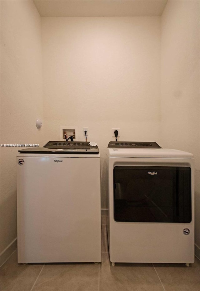 laundry area with washer and dryer, laundry area, and light tile patterned flooring