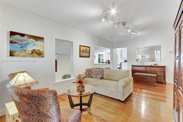 living room featuring track lighting, light wood-type flooring, and baseboards