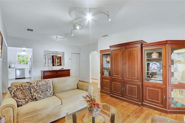 living room with visible vents, arched walkways, rail lighting, and light wood finished floors