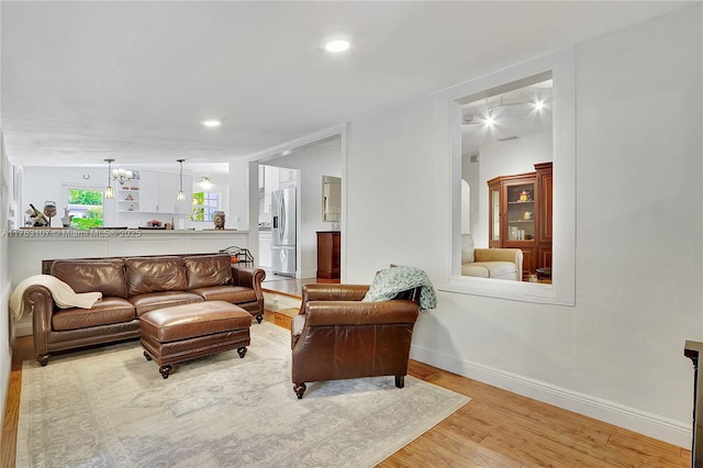 living room with recessed lighting, wood finished floors, baseboards, and a chandelier