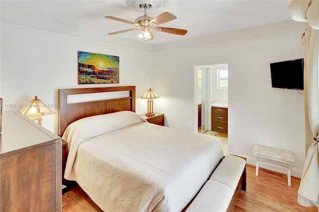 bedroom with ensuite bath, baseboards, light wood finished floors, and ceiling fan