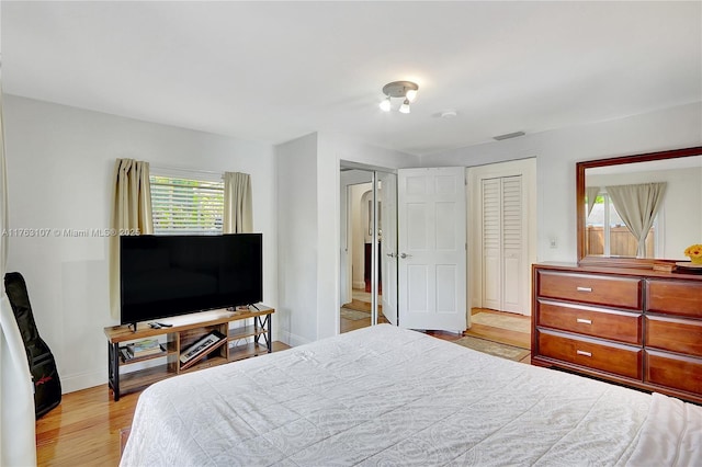 bedroom with visible vents, wood finished floors, and baseboards