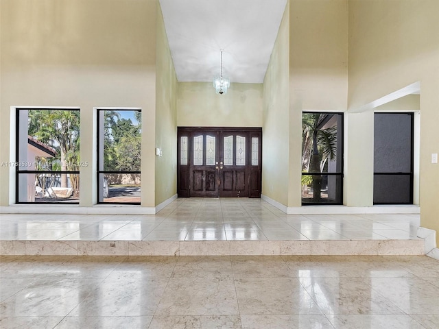 entrance foyer with a chandelier, baseboards, and a towering ceiling