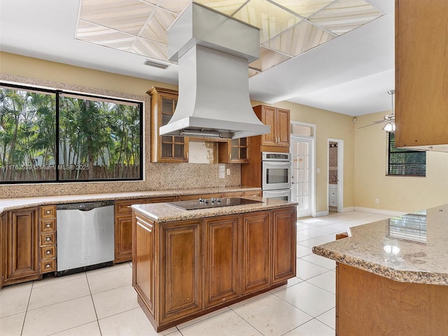 kitchen with visible vents, brown cabinets, island exhaust hood, tasteful backsplash, and stainless steel appliances