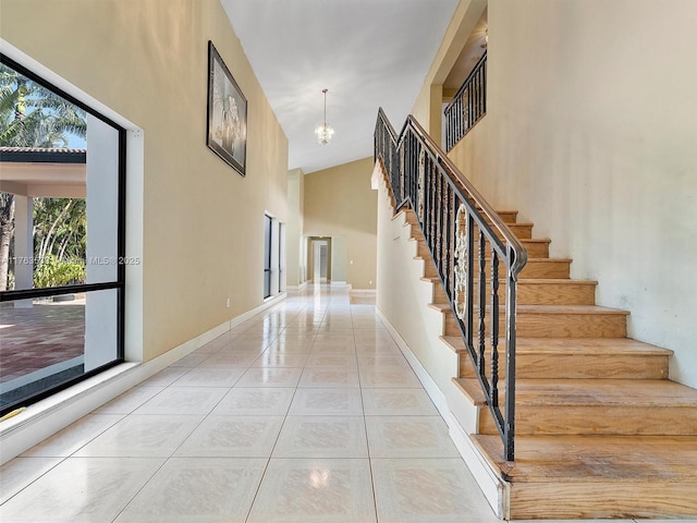 interior space featuring tile patterned floors, a high ceiling, baseboards, and a chandelier