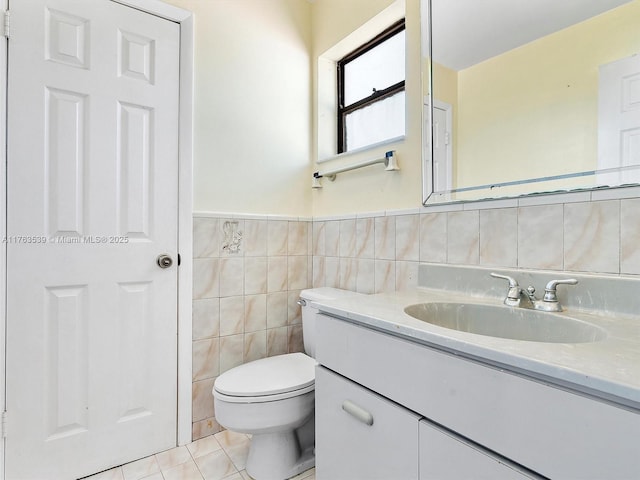 half bath with vanity, wainscoting, tile walls, toilet, and tile patterned floors