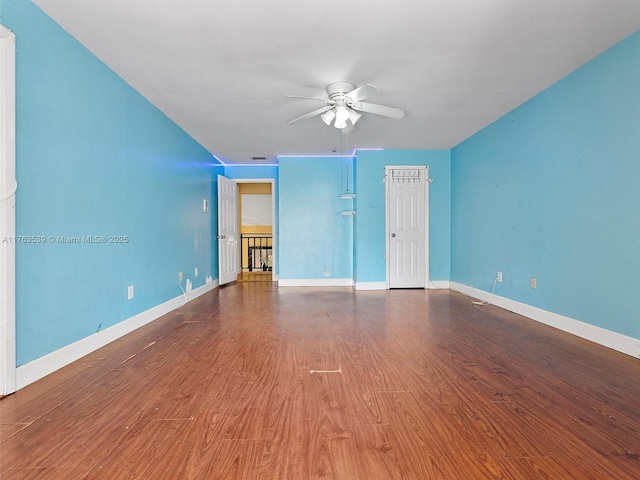 empty room with a ceiling fan, visible vents, wood finished floors, and baseboards