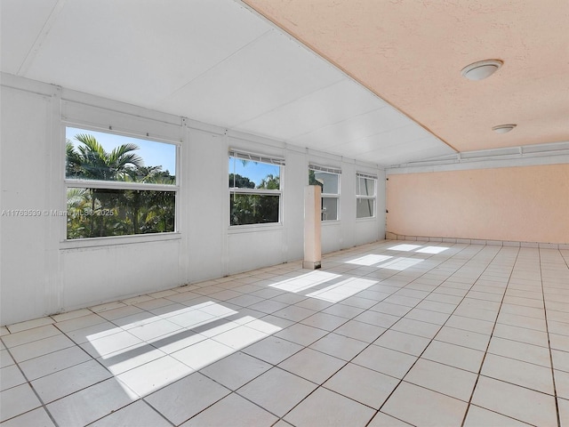 interior space with light tile patterned floors and lofted ceiling