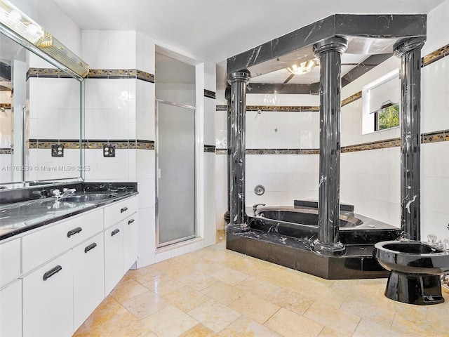 full bath featuring a garden tub, a stall shower, tile walls, vanity, and ornate columns