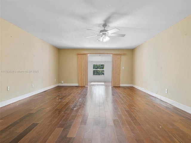 spare room featuring wood finished floors, a ceiling fan, and baseboards