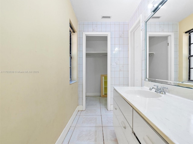 bathroom with tile patterned flooring, visible vents, and tile walls