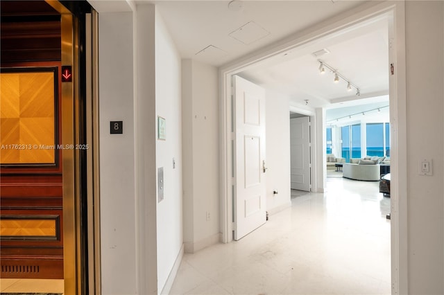 hallway featuring track lighting and baseboards