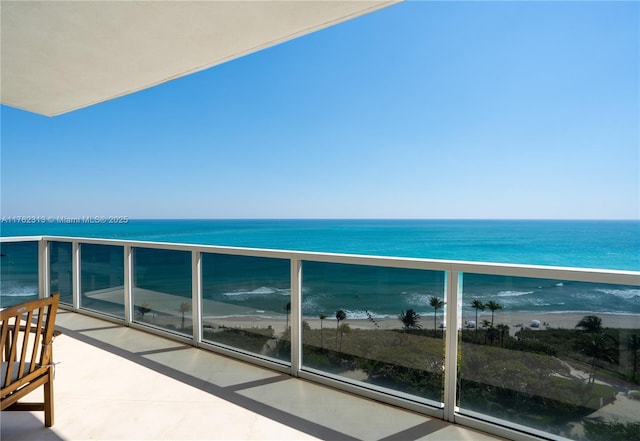 balcony with a water view and a view of the beach