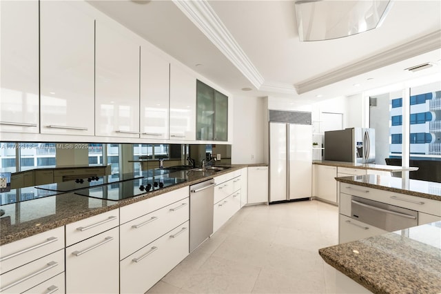 kitchen with a warming drawer, modern cabinets, ornamental molding, stainless steel appliances, and a raised ceiling