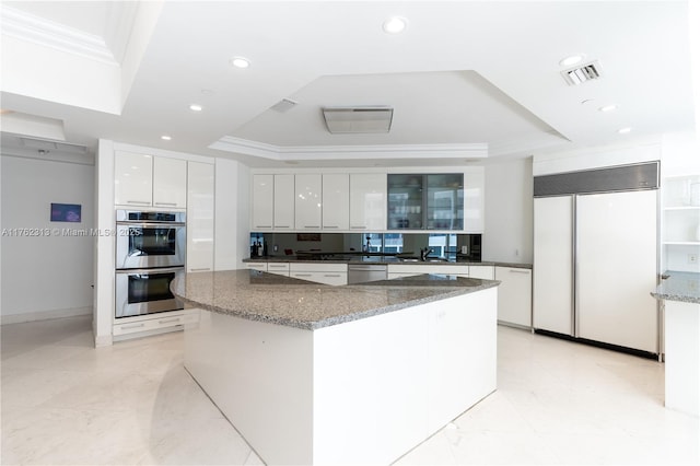 kitchen with crown molding, appliances with stainless steel finishes, white cabinetry, a raised ceiling, and modern cabinets