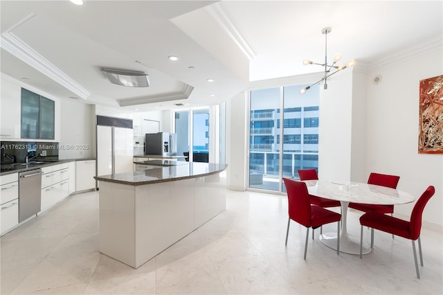 kitchen with a kitchen island, stainless steel appliances, an inviting chandelier, crown molding, and a wall of windows